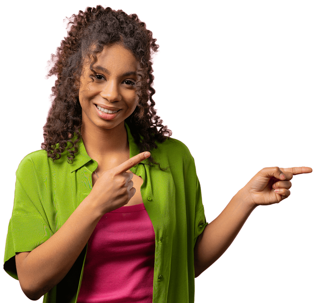 Woman with curly hair wearing a green shirt over a pink top, smiling and pointing to the right with both hands against a white background.